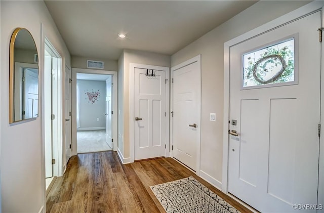 foyer entrance featuring visible vents, baseboards, and wood finished floors