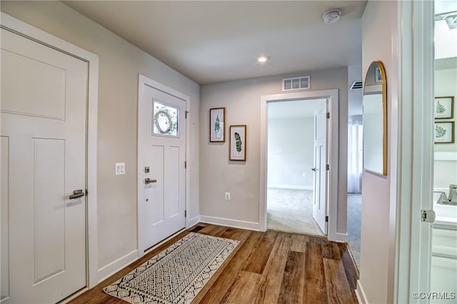 foyer with baseboards, visible vents, and wood finished floors