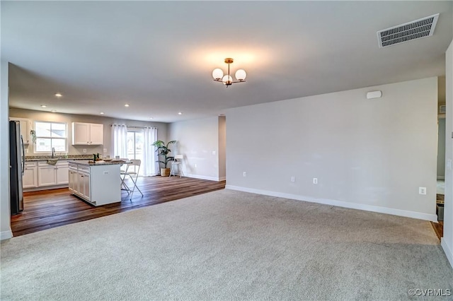 kitchen featuring visible vents, white cabinets, open floor plan, freestanding refrigerator, and a sink