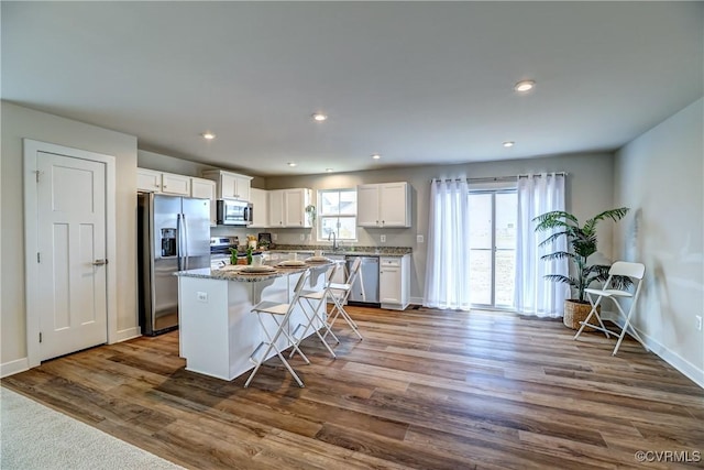 kitchen with a center island, appliances with stainless steel finishes, dark wood-type flooring, a healthy amount of sunlight, and white cabinets