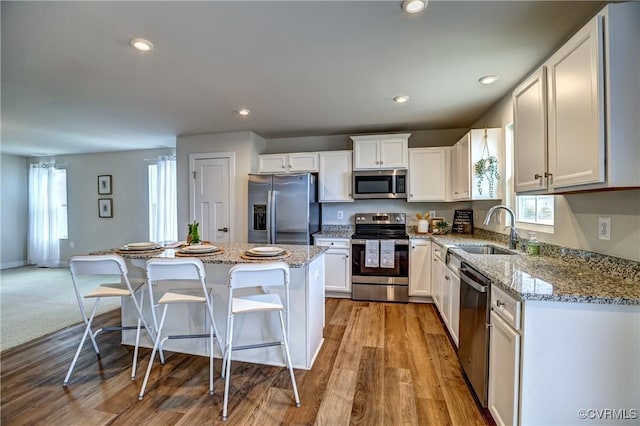 kitchen with white cabinets, a center island, stainless steel appliances, a sink, and recessed lighting