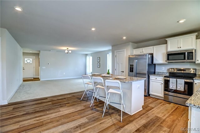 kitchen featuring light wood-style flooring, white cabinetry, stainless steel appliances, and a center island