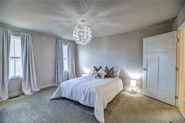 carpeted bedroom featuring a notable chandelier and baseboards