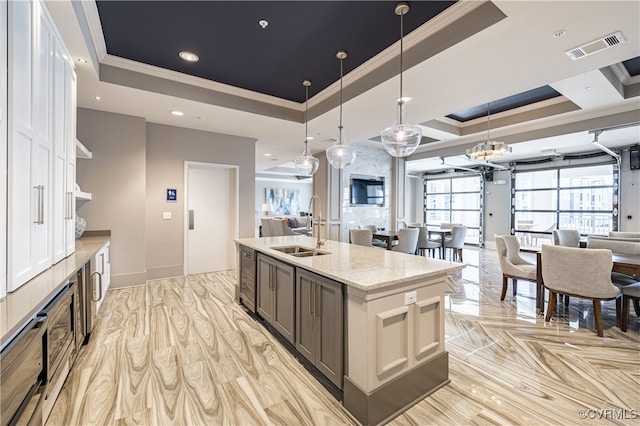 kitchen with visible vents, a tray ceiling, open shelves, a sink, and open floor plan