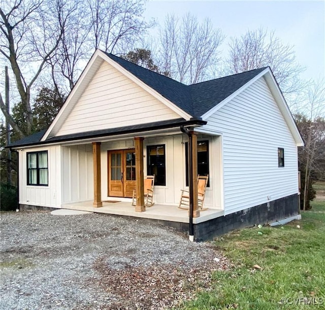 exterior space featuring roof with shingles, a porch, and board and batten siding