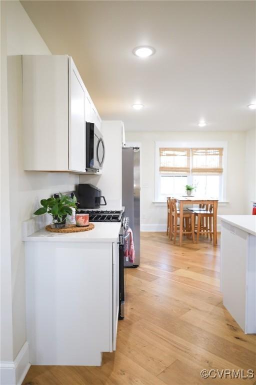 kitchen featuring appliances with stainless steel finishes, light countertops, light wood-type flooring, white cabinetry, and recessed lighting