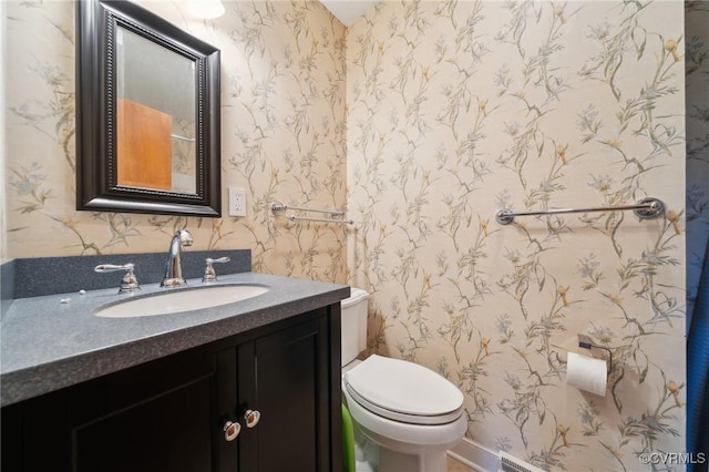 half bath featuring toilet, wallpapered walls, and vanity