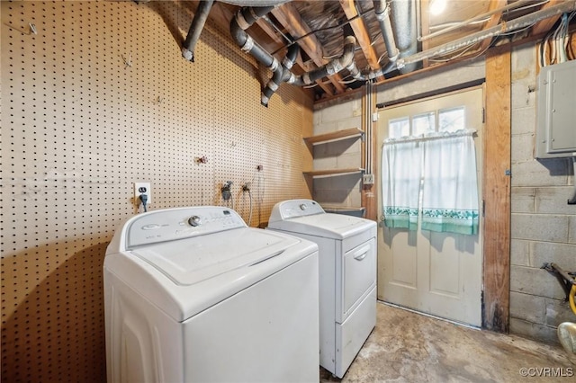 washroom featuring electric panel, washing machine and dryer, and concrete block wall