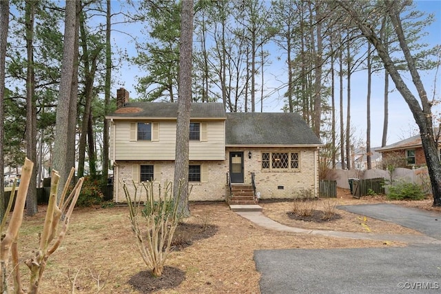 split level home with fence, driveway, a chimney, crawl space, and brick siding