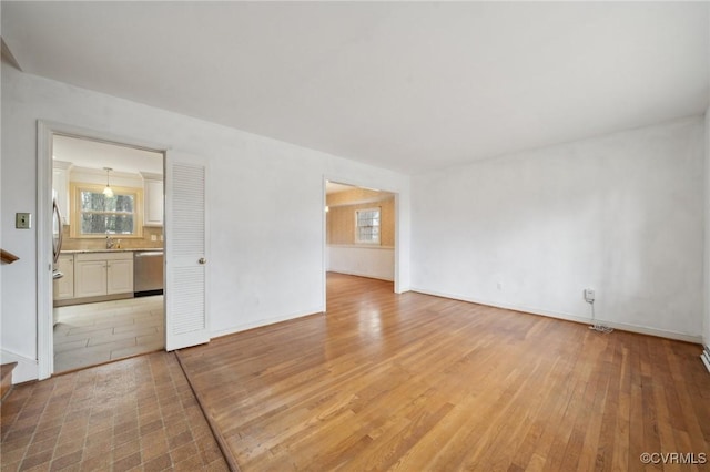 unfurnished room featuring a sink, baseboards, and light wood-style floors