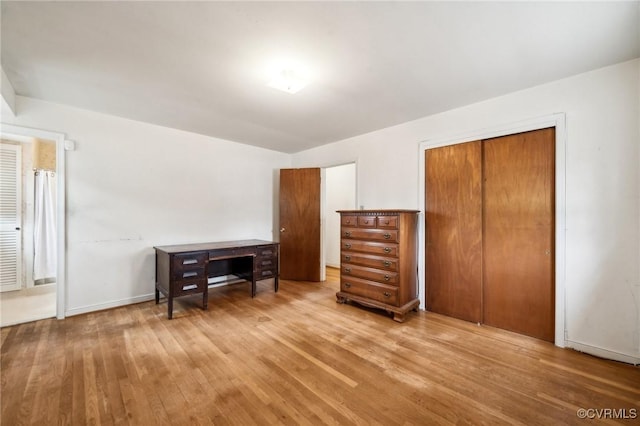 bedroom with light wood-style flooring, baseboards, and a closet