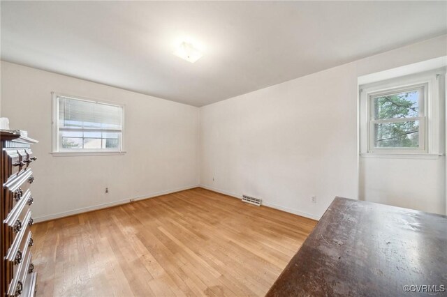 spare room with a wealth of natural light, visible vents, baseboards, and light wood-style floors