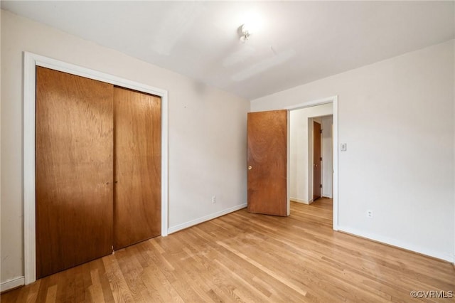 unfurnished bedroom with baseboards, light wood-type flooring, and a closet