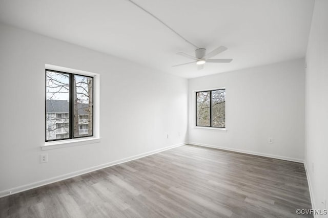 unfurnished room with wood finished floors, baseboards, and ceiling fan