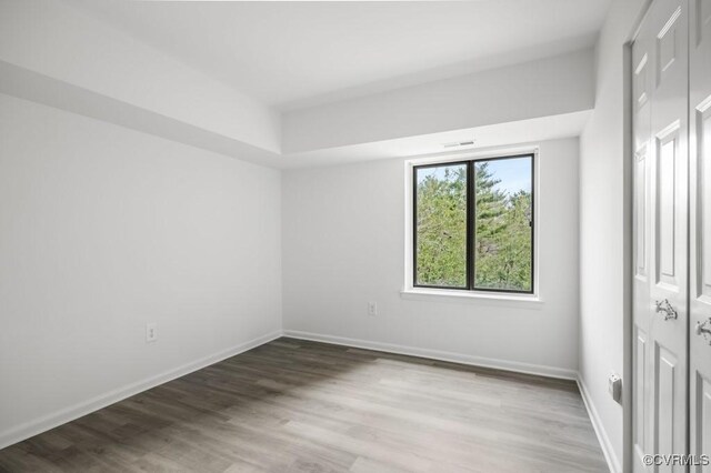 unfurnished bedroom with visible vents, baseboards, a closet, and wood finished floors