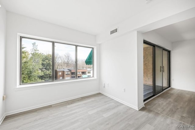 unfurnished room with wood finished floors, visible vents, and baseboards