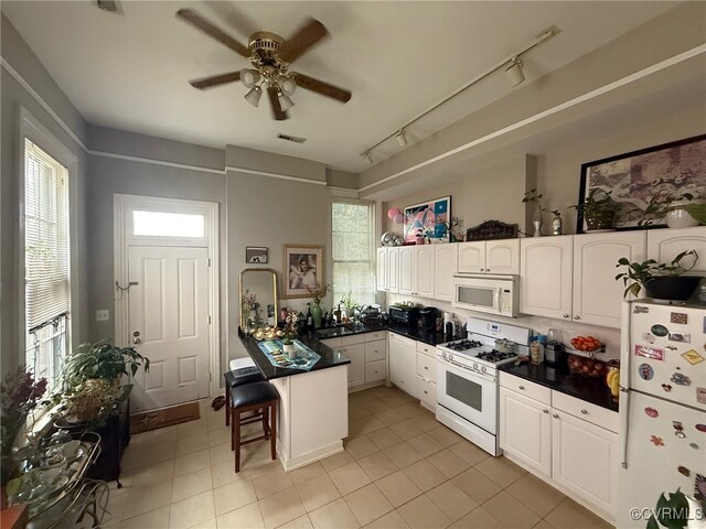 1005 W Franklin St Unit U2, Richmond, VA 23220 - kitchen with a breakfast bar, a peninsula, white appliances, dark countertops, and white cabinets