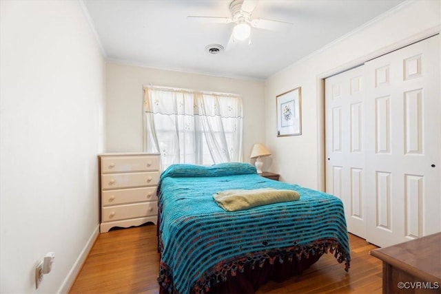 bedroom featuring visible vents, baseboards, ornamental molding, wood finished floors, and a closet