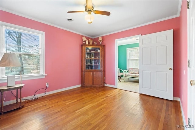 empty room with crown molding, light wood-style flooring, baseboards, and visible vents