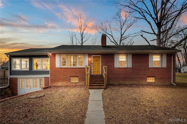 view of front of house with brick siding, crawl space, and a chimney