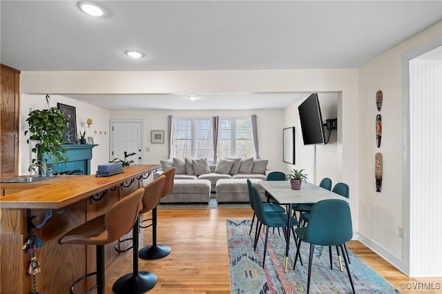 dining space with recessed lighting, light wood-style flooring, a fireplace, and baseboards