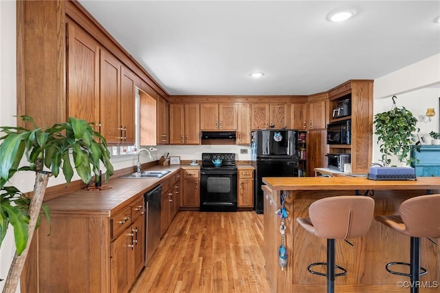 kitchen featuring black appliances, extractor fan, brown cabinets, and a sink