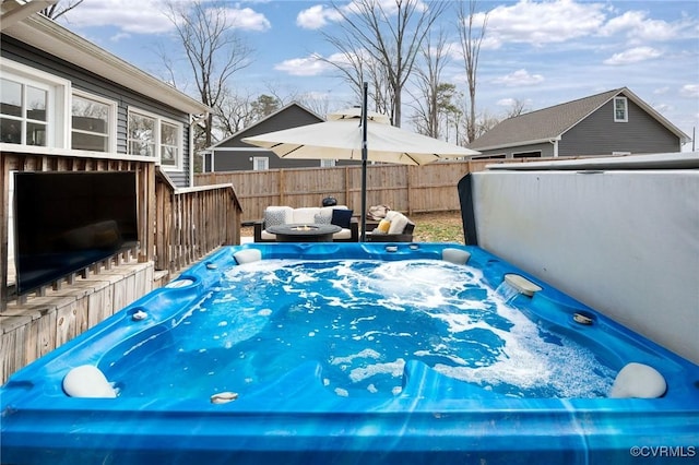 view of pool with a wooden deck, fence, and a hot tub