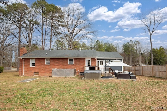 rear view of property featuring fence, a yard, brick siding, a chimney, and a hot tub