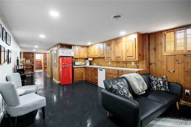 kitchen with wooden walls, light countertops, concrete flooring, recessed lighting, and white appliances