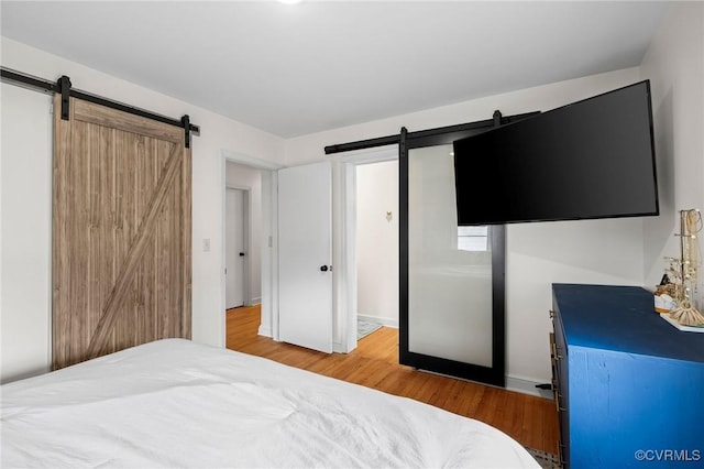 bedroom with a barn door and wood finished floors