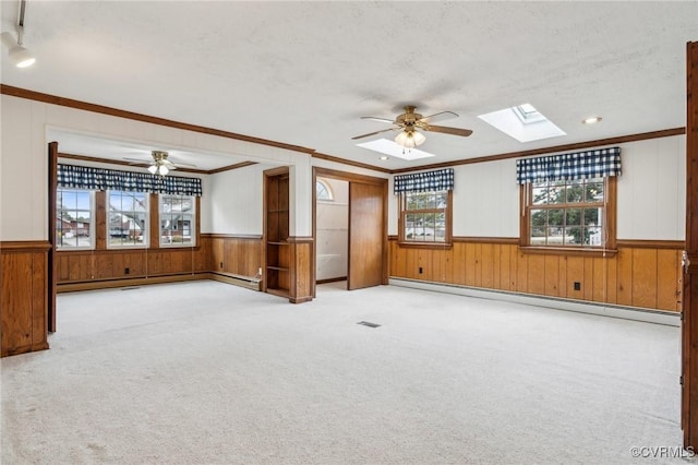 carpeted empty room with baseboard heating, a skylight, and ceiling fan