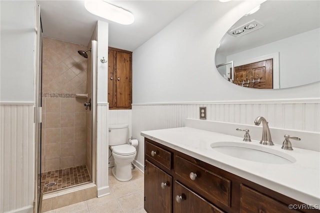 full bath with toilet, a stall shower, wainscoting, and tile patterned flooring