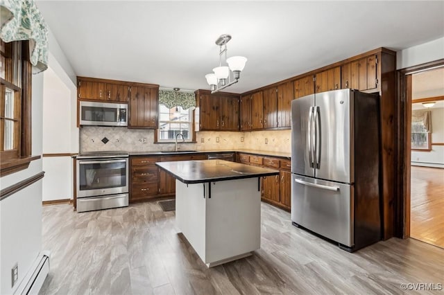 kitchen with dark countertops, baseboard heating, appliances with stainless steel finishes, and a sink