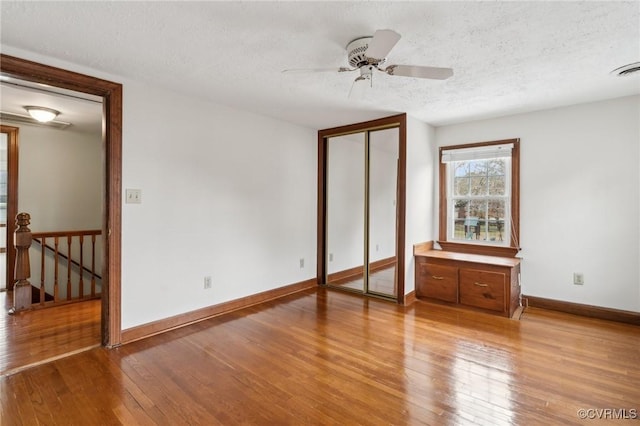 unfurnished bedroom featuring visible vents, baseboards, a textured ceiling, and light wood finished floors