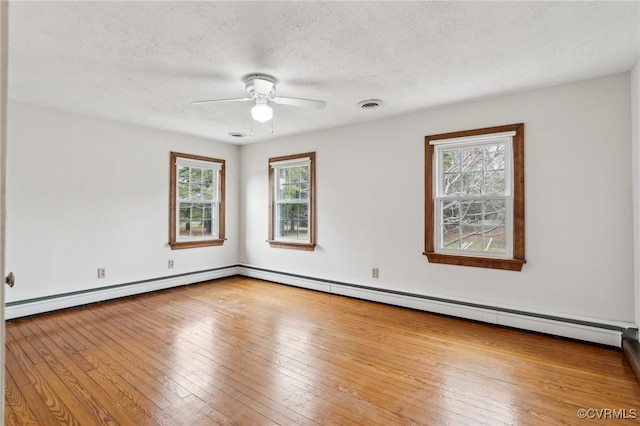 unfurnished room featuring visible vents, ceiling fan, hardwood / wood-style flooring, a textured ceiling, and a baseboard heating unit