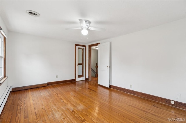 empty room with a baseboard radiator, visible vents, baseboards, and light wood finished floors