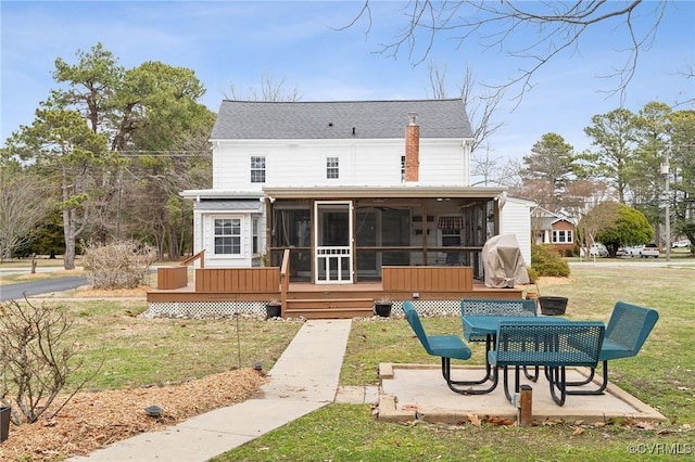 back of property featuring a deck, a yard, roof with shingles, a sunroom, and a patio area