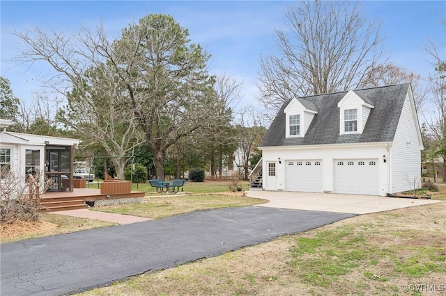 view of front of home with roof with shingles, a wooden deck, a sunroom, a front lawn, and a garage