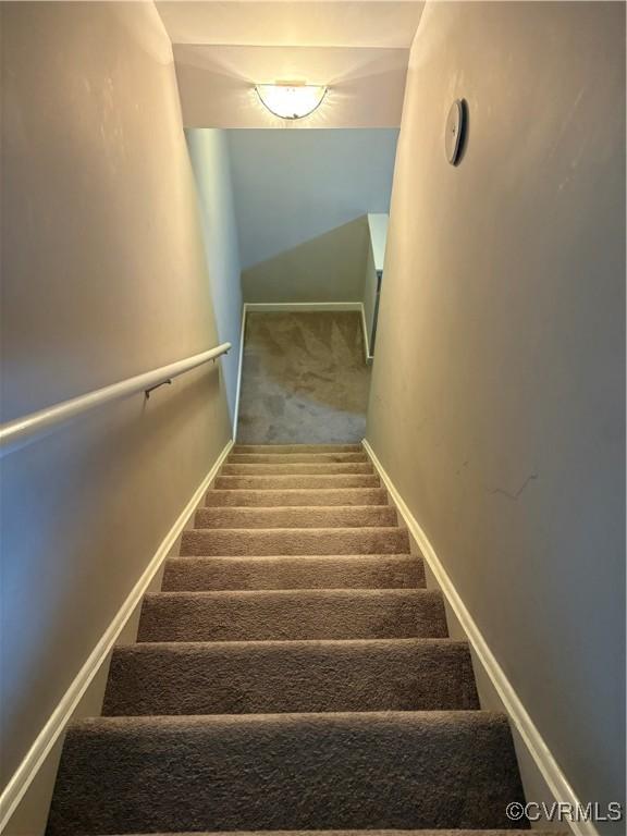 stairway featuring baseboards and carpet