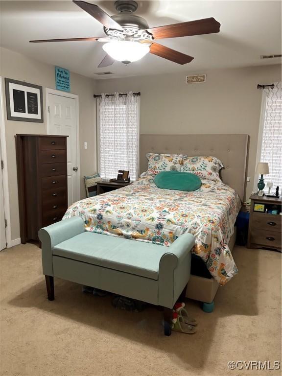 bedroom with visible vents, multiple windows, light carpet, and ceiling fan