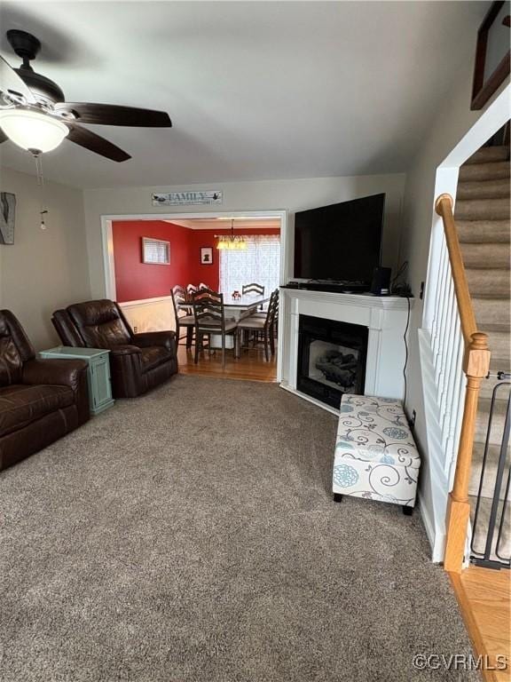 living room featuring ceiling fan, carpet floors, a fireplace, and stairs