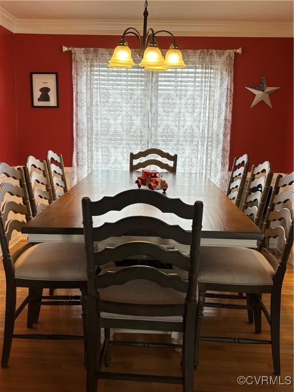 dining room featuring wood finished floors, a notable chandelier, and ornamental molding