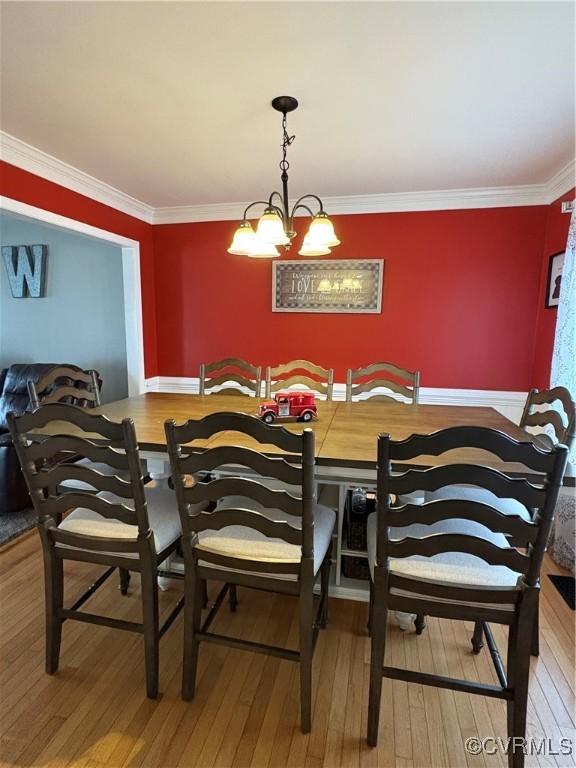 dining room featuring crown molding, an inviting chandelier, and hardwood / wood-style flooring