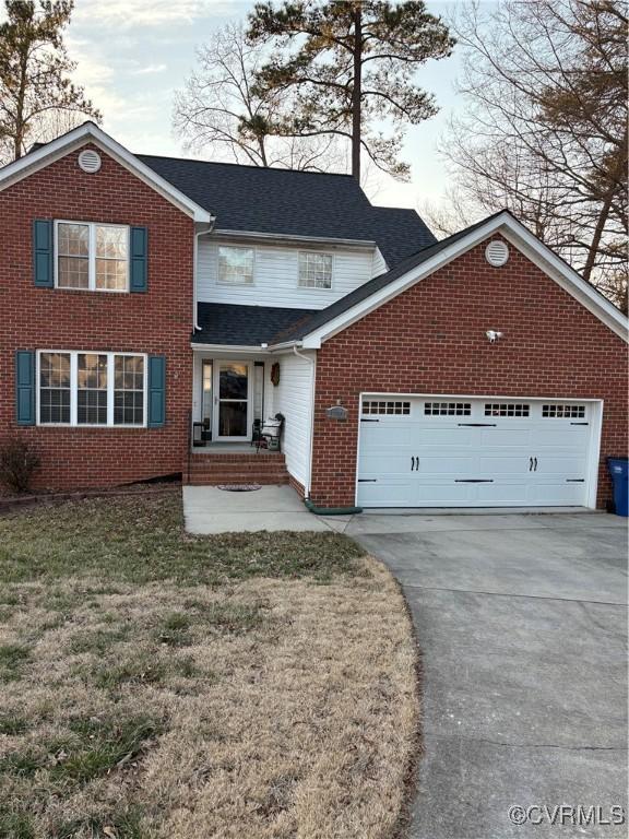 traditional home featuring a front lawn, concrete driveway, an attached garage, a shingled roof, and brick siding