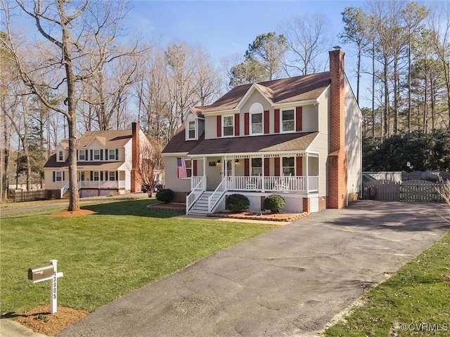 view of front facade featuring fence, a porch, a chimney, a front lawn, and aphalt driveway