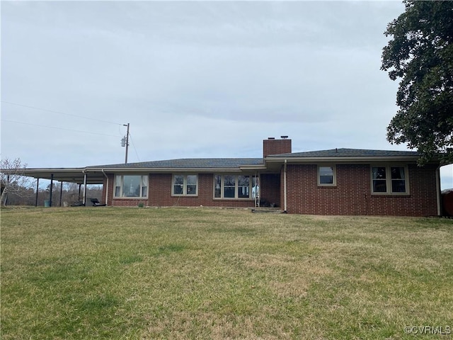 view of front facade with an attached carport, a front yard, brick siding, and a chimney