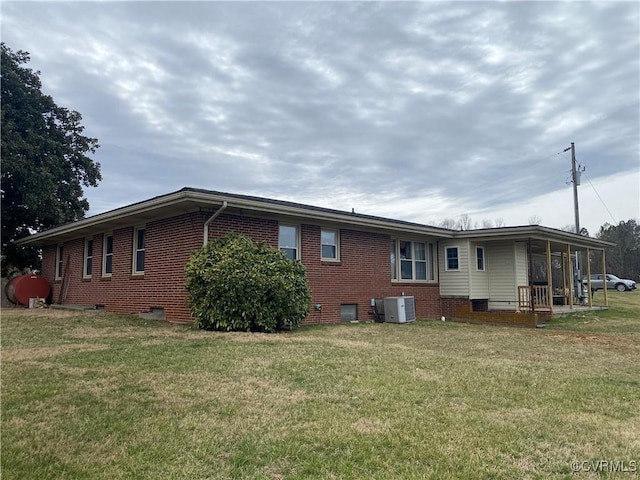 back of property with crawl space, brick siding, cooling unit, and a yard