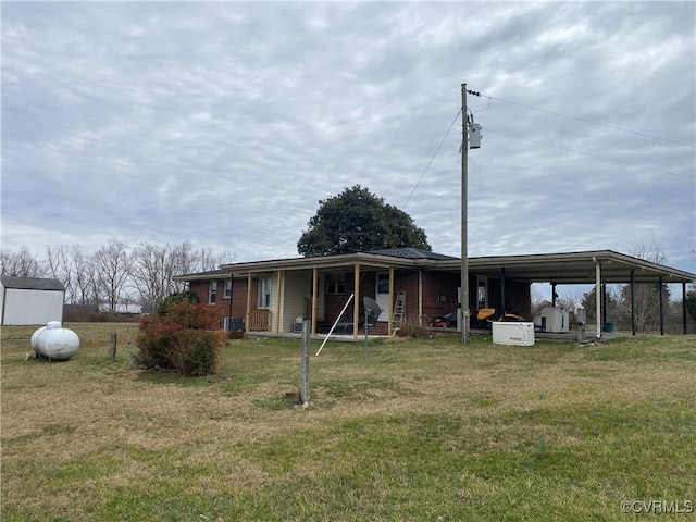 back of property with a yard, a carport, a porch, and brick siding