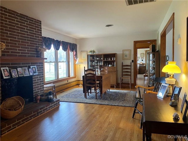 office area with visible vents, wood finished floors, and a fireplace