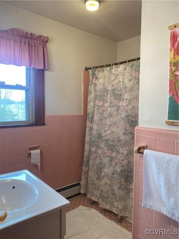 bathroom with curtained shower, tile walls, wainscoting, baseboard heating, and vanity